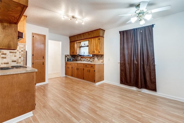 kitchen with decorative backsplash, sink, light hardwood / wood-style floors, and a textured ceiling