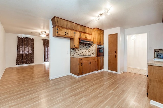 kitchen with gas stovetop, range hood, oven, decorative backsplash, and light wood-type flooring