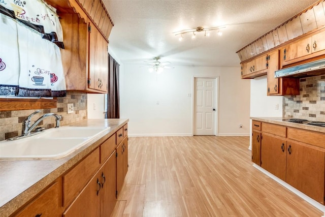 kitchen with backsplash, sink, light hardwood / wood-style flooring, ceiling fan, and a textured ceiling