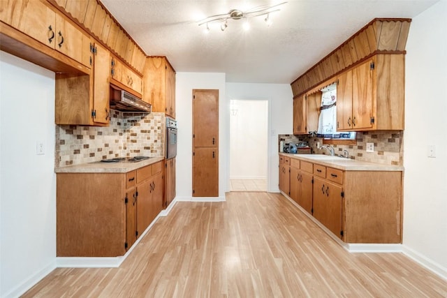 kitchen with sink, stainless steel appliances, a textured ceiling, and light hardwood / wood-style flooring