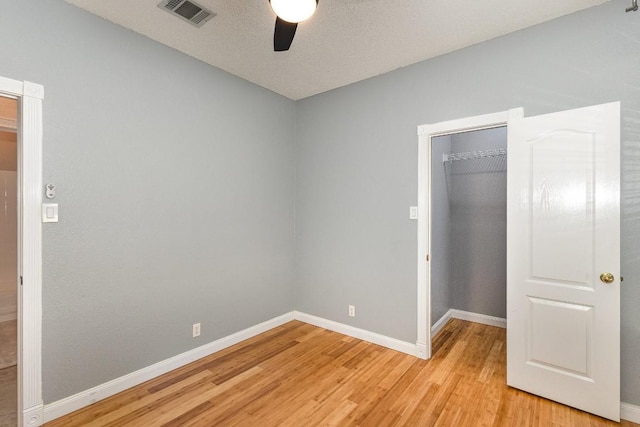 unfurnished bedroom with ceiling fan, a closet, light hardwood / wood-style floors, and a spacious closet