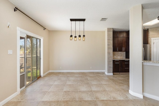 unfurnished dining area featuring light tile patterned flooring and a textured ceiling