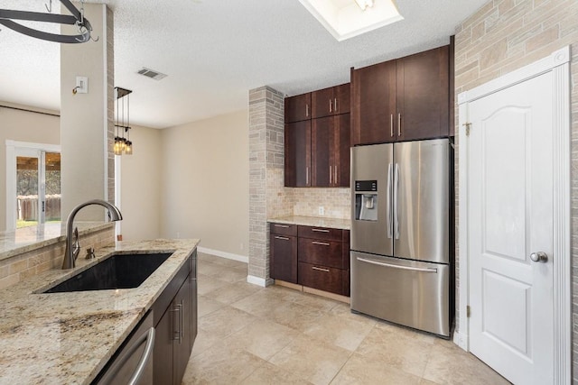 kitchen featuring a textured ceiling, decorative light fixtures, sink, and stainless steel appliances