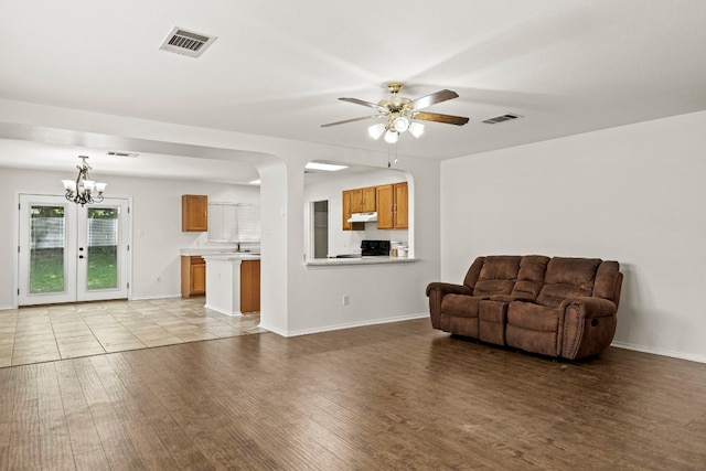 unfurnished living room featuring french doors, ceiling fan with notable chandelier, and light hardwood / wood-style floors