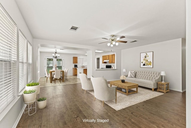 living room with dark hardwood / wood-style floors and ceiling fan with notable chandelier