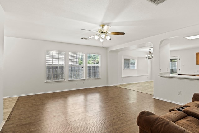 living room featuring ceiling fan with notable chandelier and dark wood-type flooring