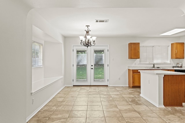 kitchen with french doors, sink, light tile patterned floors, a chandelier, and hanging light fixtures