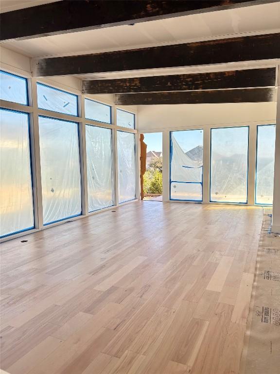 unfurnished room featuring beam ceiling, expansive windows, and hardwood / wood-style floors