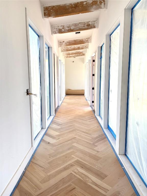 hall featuring plenty of natural light, beam ceiling, and light parquet flooring