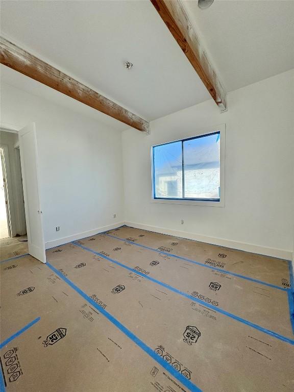 spare room featuring beamed ceiling