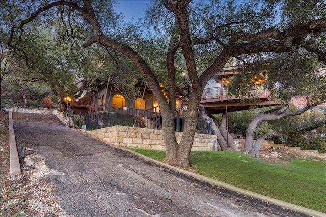 view of property hidden behind natural elements with a wooden deck and a front lawn