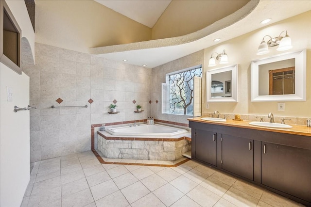 bathroom featuring tile patterned flooring, a relaxing tiled tub, tile walls, and vanity