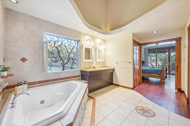 bathroom with tile patterned floors, vanity, a textured ceiling, and tiled bath