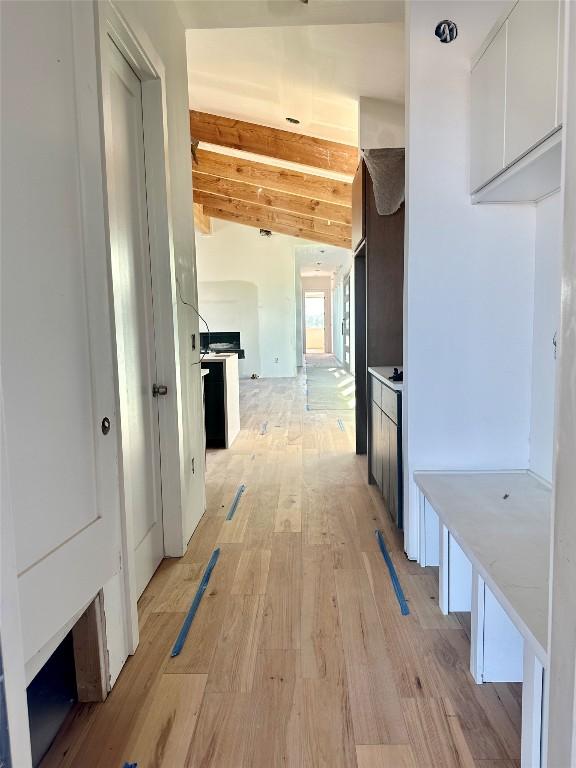 hall featuring vaulted ceiling with beams and light wood-type flooring