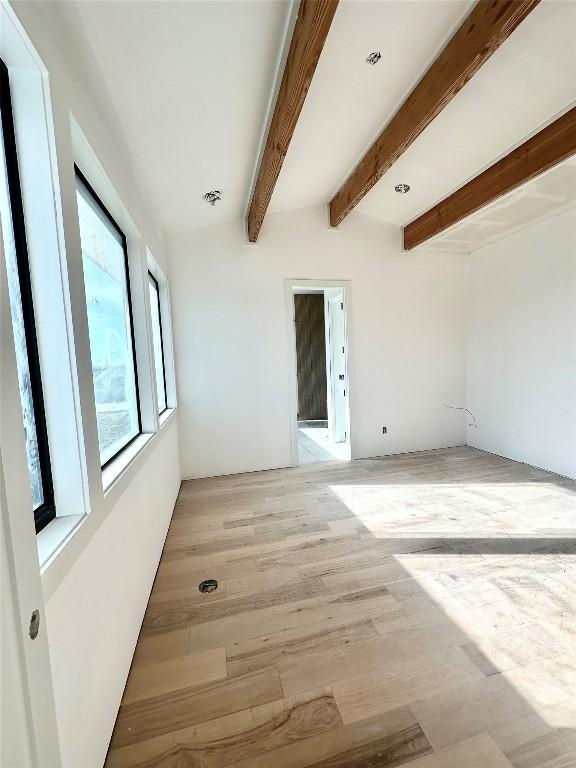 unfurnished room with lofted ceiling with beams and light hardwood / wood-style flooring