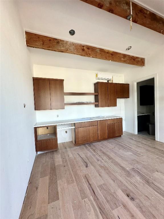 kitchen with beamed ceiling, built in desk, and light hardwood / wood-style floors