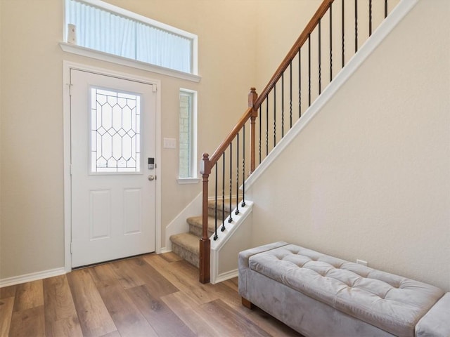 entryway with baseboards, stairway, a high ceiling, and wood finished floors