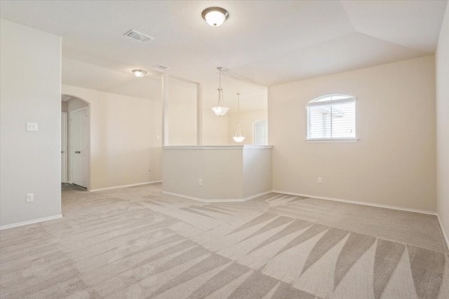 empty room with arched walkways, baseboards, visible vents, and light colored carpet