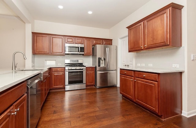 kitchen featuring sink, light stone counters, dark hardwood / wood-style flooring, backsplash, and appliances with stainless steel finishes