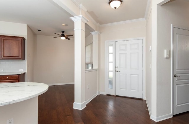 foyer with ceiling fan, dark wood-type flooring, crown molding, and decorative columns