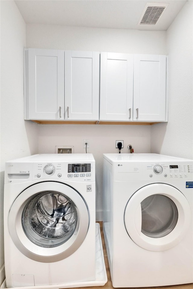 laundry area with washing machine and dryer and cabinets