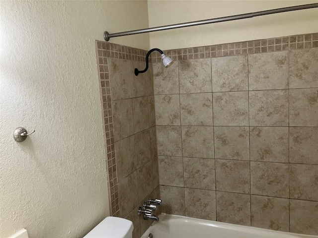 bathroom featuring tiled shower / bath combo and toilet