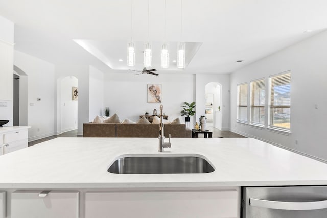 kitchen with white cabinetry, sink, dishwasher, ceiling fan, and a center island with sink