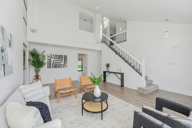 living room with a towering ceiling and light hardwood / wood-style flooring