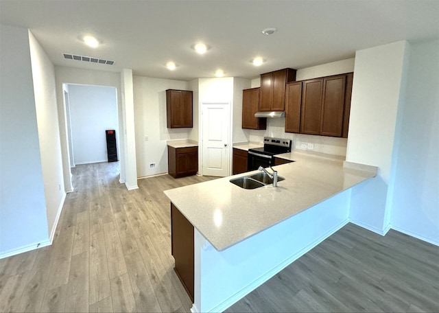 kitchen with sink, dark brown cabinetry, light hardwood / wood-style floors, black range with electric cooktop, and kitchen peninsula