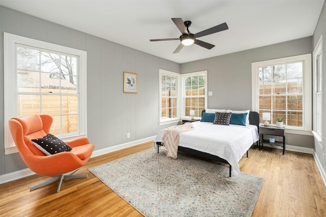 bedroom featuring ceiling fan, light hardwood / wood-style flooring, and multiple windows