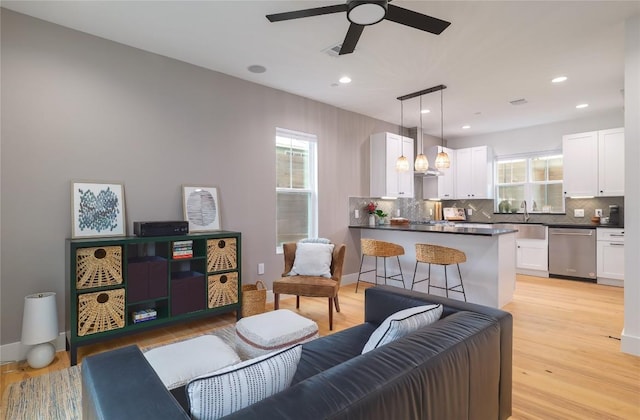 living room with ceiling fan, sink, a healthy amount of sunlight, and light wood-type flooring