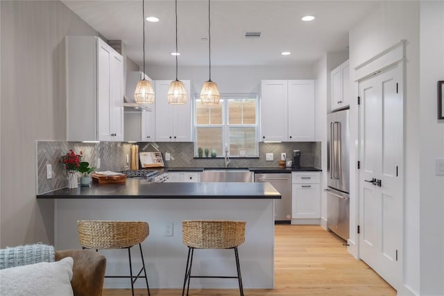 kitchen with hanging light fixtures, white cabinetry, sink, and appliances with stainless steel finishes