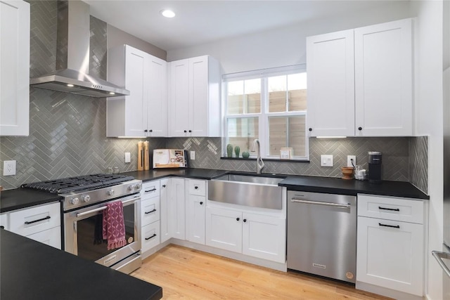 kitchen featuring white cabinetry, sink, wall chimney exhaust hood, tasteful backsplash, and appliances with stainless steel finishes