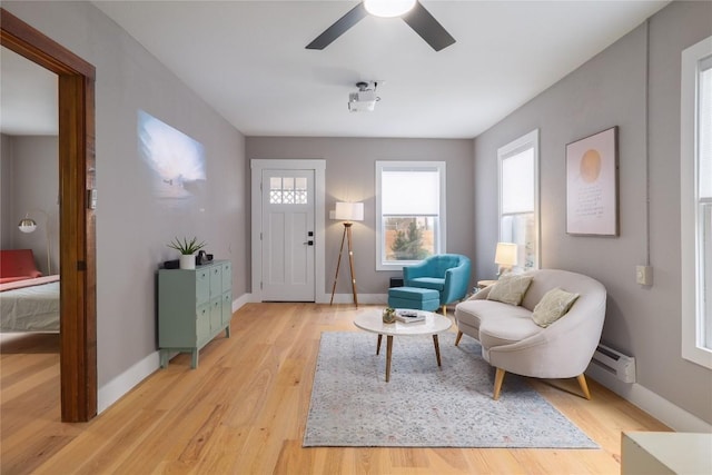 interior space with baseboard heating, ceiling fan, and light hardwood / wood-style floors