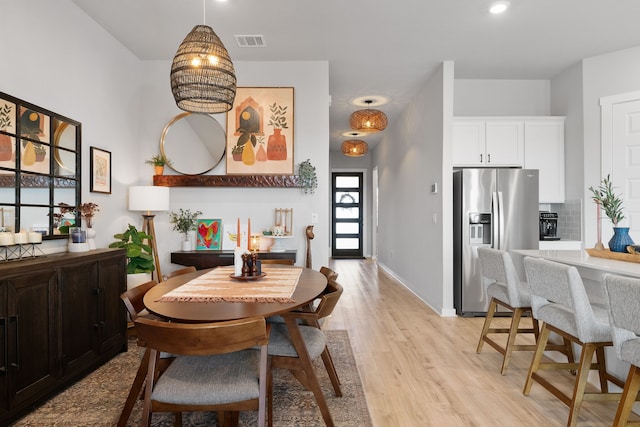 dining room featuring light wood-style flooring, visible vents, and baseboards