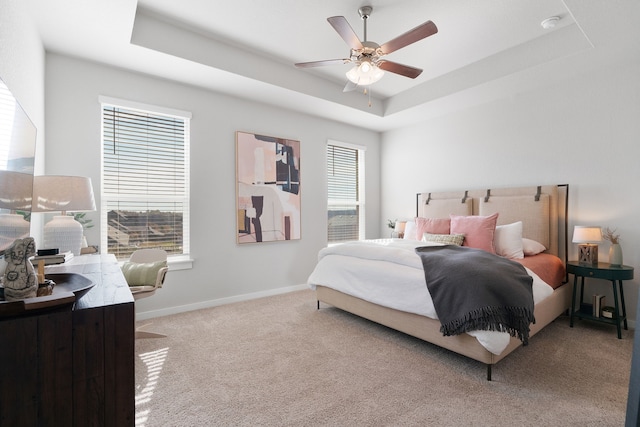 bedroom with a raised ceiling, carpet flooring, ceiling fan, and baseboards