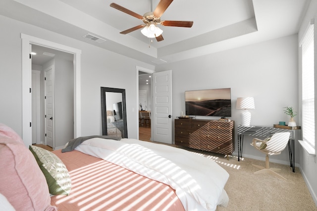 bedroom with a tray ceiling, carpet flooring, visible vents, and baseboards