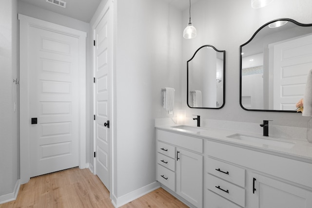 bathroom with double vanity, visible vents, a sink, and wood finished floors