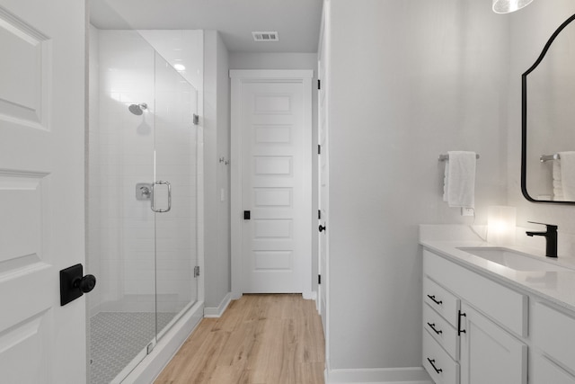 full bathroom featuring vanity, wood finished floors, a shower stall, and visible vents