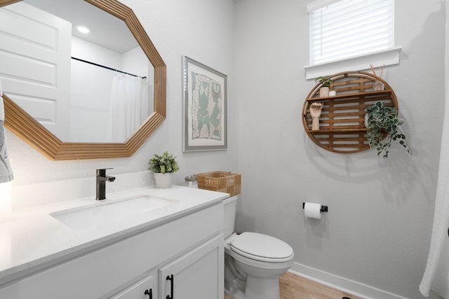 full bathroom featuring toilet, baseboards, wood finished floors, and vanity