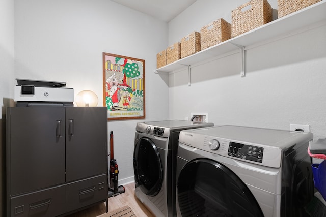 laundry room with laundry area, washing machine and clothes dryer, and light wood-style flooring