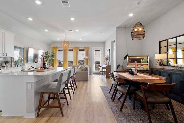 dining area with vaulted ceiling and light hardwood / wood-style floors