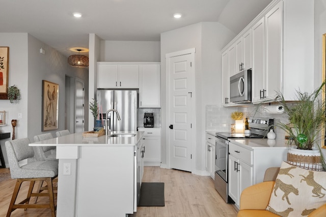 kitchen with stainless steel appliances, tasteful backsplash, light countertops, and white cabinets