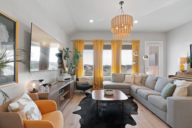 living room featuring lofted ceiling, light hardwood / wood-style floors, and a chandelier