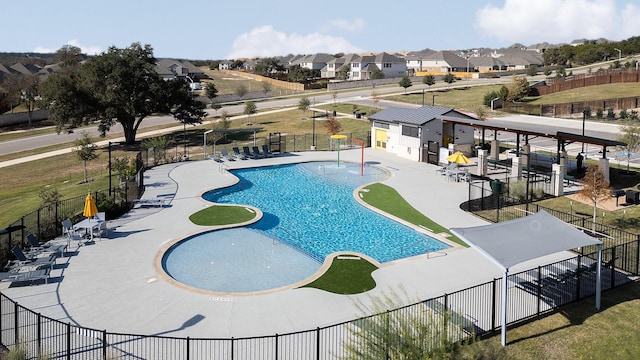 community pool with a patio area, fence, and a residential view