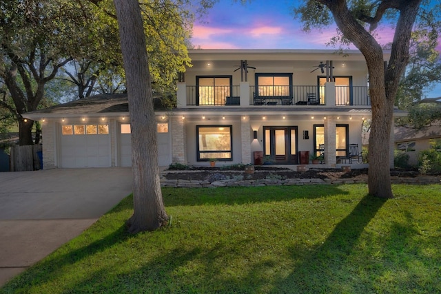 view of front of house featuring a lawn, ceiling fan, a garage, and a balcony