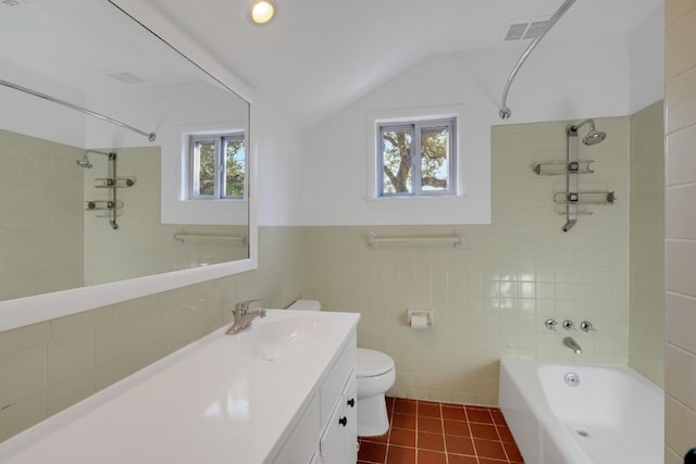 full bathroom featuring vanity, vaulted ceiling, tile patterned flooring, toilet, and tile walls