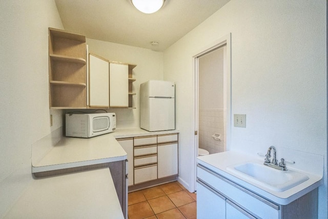 bathroom with toilet, sink, and tile patterned flooring