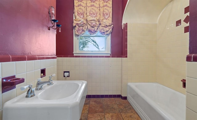 bathroom featuring sink, a bath, and tile walls