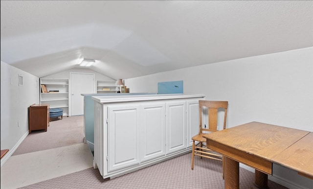 carpeted home office featuring vaulted ceiling